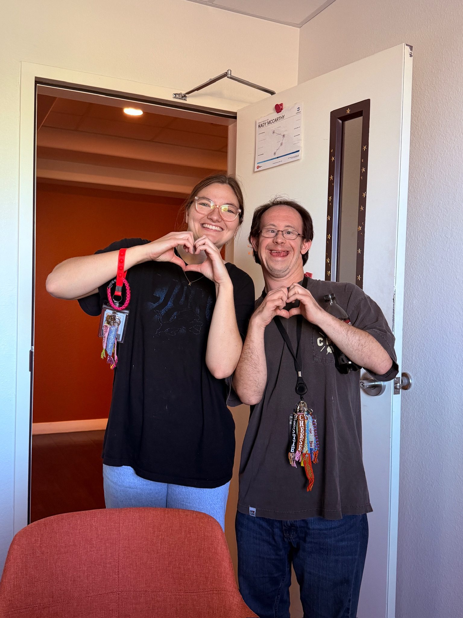 A Treasure House coach and resident making heart shapes with their hands